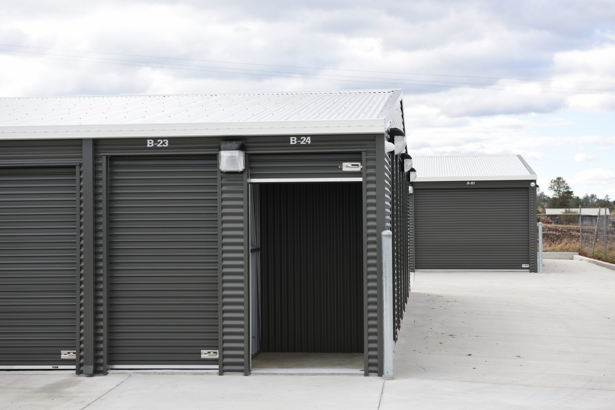 An row of modern storage units with grey roller doors and corrugated metal walls